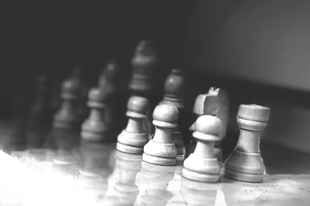 Black and white image of a chess board with chess figures while playing as a hobby.