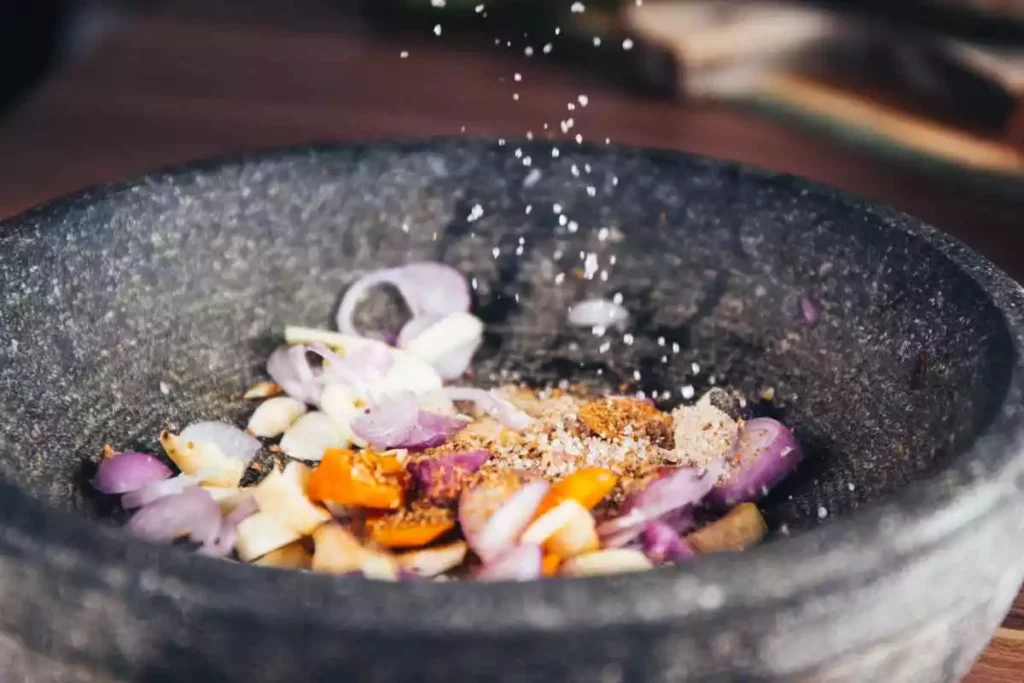 Seasoning onions, carrots, and other vegetables with salt in a decorative plate. 
