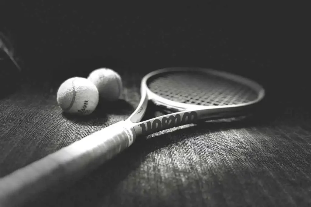 Wilson Clash 100 Tennis Racquet with Wilson Roland Garros Tennis balls in a black and white photograph.