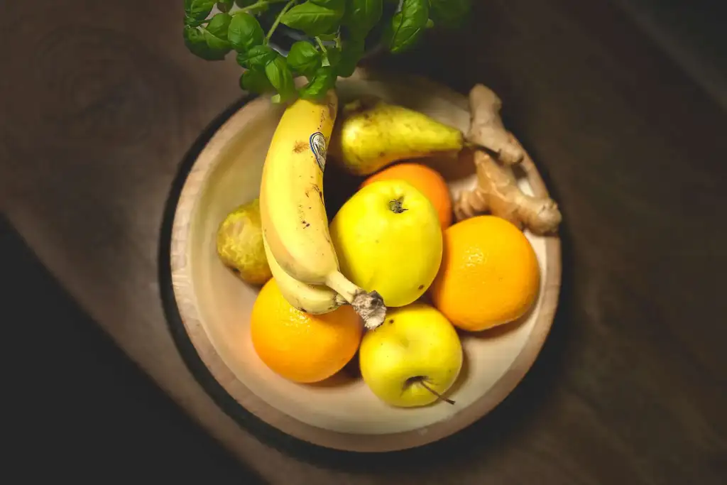 A photograph of the best foods to stay energetic at work and improve productivity, such as banana, orange, apple, ginger, pear, and basil.