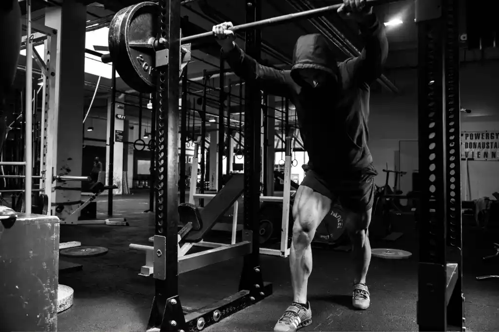 A black and white photograph of a bodybuilder in the gym, practicing. Bodybuilding is a great sport for shorter men and women. 