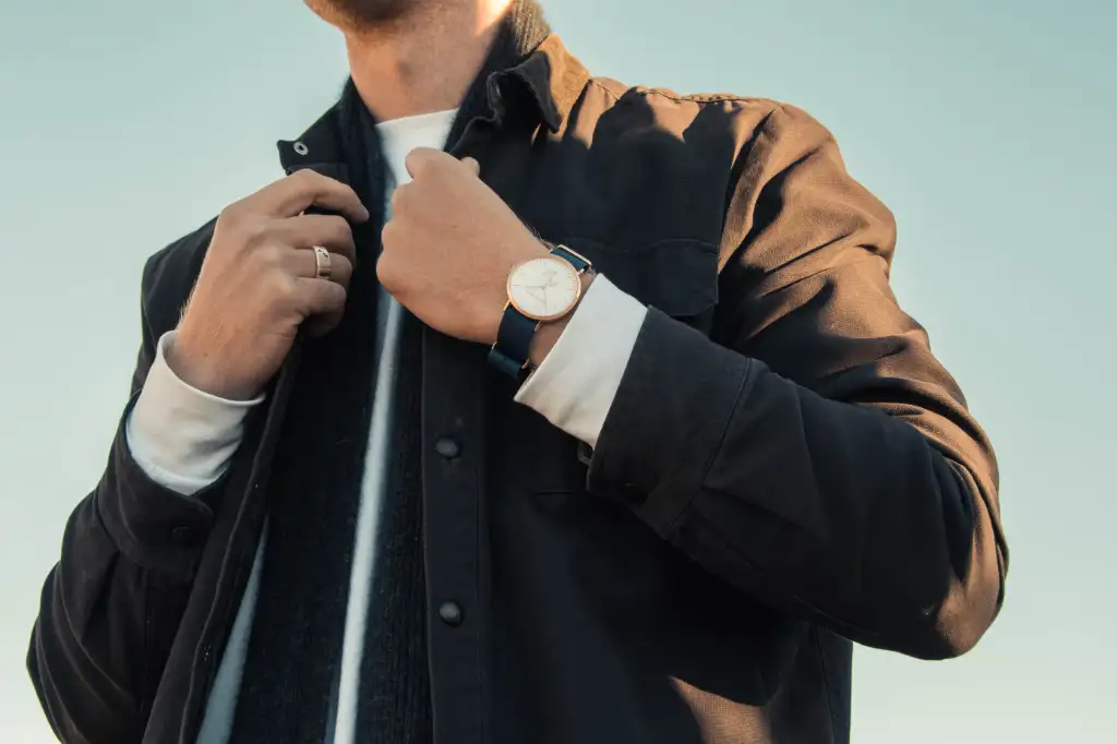 A photograph of a well-dressed and clean young man looking to impress his crush, wearing a nice coat paired with a scarf and a gold watch and wedding ring.